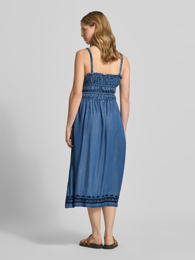 Vrouwenmodel draagt Tailliertes Jeanskleid aus Lyocell van Pepe Jeans in denimlook, getailleerd, midilengte, vierkante hals, applicatie met kwastjes, borduursel, elastische borstbanden, naadritssluiting, tunnelkoord, smalle bandjes, materiaal lyocell. Volledige lichaamsaanzicht achterkant.