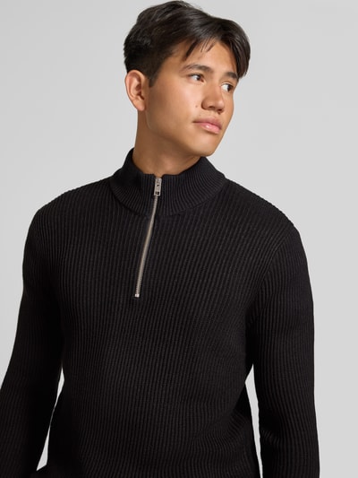 Männermodel trägt Strickpullover mit Troyer-Kragen Modell 'PANNEL' von JACK & JONES, Schwarz, Rippstruktur, Material-Mix, Nahaufnahme Oberkörper.
