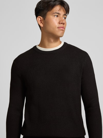 Męski model nosi sweter z dzianiny z mieszanki materiałów z bawełną, dopasowany krój, okrągły dekolt, Model 'PANNEL' od JACK & JONES, Długość tyłu 70 cm, długość rękawów 71 cm, widok na górną część ciała z przodu.