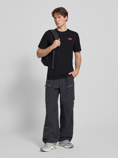 Mannenmodel draagt T-shirt met Logo en ronde hals van The North Face in zwart, katoenmix, regular fit, ruglengte maat M 72 cm. Ganzlichaamsaanzicht van voren.