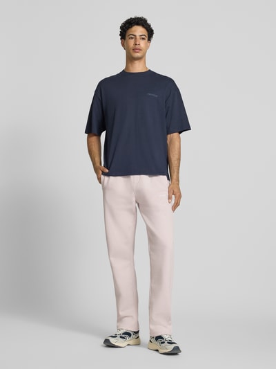 Männermodel trägt Straight Fit Sweatpants mit Logo-Stitching von Pegador in Creme, Baumwoll-Mix, elastischer Bund, Ganzkörperansicht von vorne.