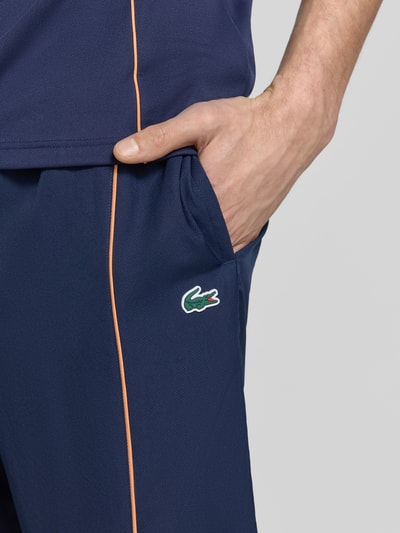 Männermodel trägt Regular Fit Sport-Shorts mit weichem Innenstoff von Lacoste Sport in Dunkelblau mit Strukturmuster und Label Patch, Nahaufnahme Oberkörper