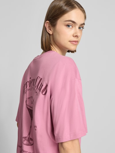 Frauenmodel trägt Oversized Fit T-Shirt aus reiner Baumwolle mit Label-Detail von REVIEW, Print auf der Rückseite, Nahaufnahme Oberkörper.