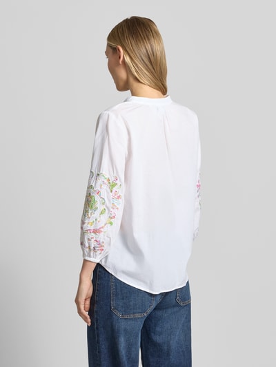 Frauenmodel trägt Bluse mit Schlüsselloch-Ausschnitt und Schnürung von Emily Van den Bergh aus Reine Baumwolle, Straight Fit, 3/4-Arm, elastische Ärmelabschlüsse, abgerundeter Saum, Rückenlänge bei Größe 36: 62 cm, Ärmellänge bei Größe 36: 50 cm, weiß mit bunten Stickereien, lockere Textur, Ganzkörperansicht Rückansicht.