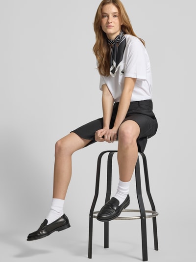 Frauenmodel trägt Damen T-Shirt mit Brusttasche und Label-Detail von Carhartt Work In Progress aus Reine Baumwolle, Regular-Fit, Rundhalsausschnitt, Schwarz-Weiß-Kontrast, Rückenlänge 59 cm bei Größe S, Ganzkörperansicht von vorne.