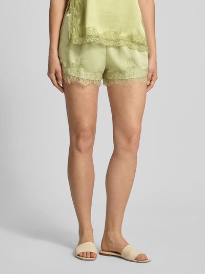 Frauenmodel trägt Shorts aus Satin mit Spitzenbesatz von Gina Tricot in Hellgrün, Regular-Fit, elastischer Bund mit Tunnelzug, Nahaufnahme Unterkörper. Bundweite 41 cm und Innenbeinlänge 9 cm bei Größe S.