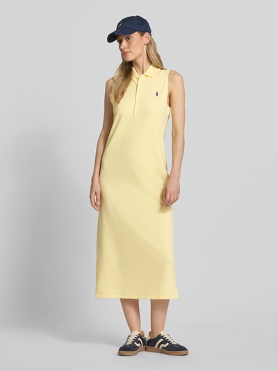 Kobiece modelka nosi Figurumschpielendes Polokleid aus Baumwoll-Mix von Polo Ralph Lauren w jednolitym, pastelowo-żółtym kolorze, długość midi, bez rękawów, z polokołnierzykiem, zapięcie na krótką listwę guzikową, materiał bawełniany piké z bocznym rozcięciem, prosta faktura, logo na piersi, widok całej sylwetki z przodu.