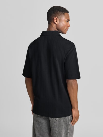 Männermodel trägt Relaxed Fit Poloshirt mit Strukturmuster Modell 'DALIBO' von HUGO, Optik: Unifarben, reine Baumwolle, Ganzkörperansicht Rückansicht.