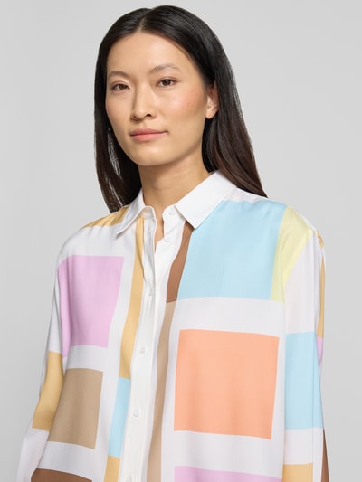 Kobiece modelka nosi Boxy Fit Bluse im Allover-Look od HERZENS, mieszanka materiałów z dodatkiem streczu, kołnierzyk koszulowy, listwa guzikowa, kolorowe geometryczne wzory, długość tyłu 59 cm, długość rękawów 61 cm, ujęcie zbliżeniowe górnej części ciała.