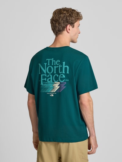 Männermodel trägt Relaxed Fit T-Shirt mit Logo-Print von The North Face aus reiner Baumwolle in Dunkelgrün, Rückenansicht, Ganzkörperansicht Rückansicht.