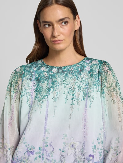 Frauenmodel trägt Regular Fit Bluse mit Rundhalsausschnitt von Marc Cain im schimmernden Allover-Look mit Knopfverschluss, Nahaufnahme Oberkörper.