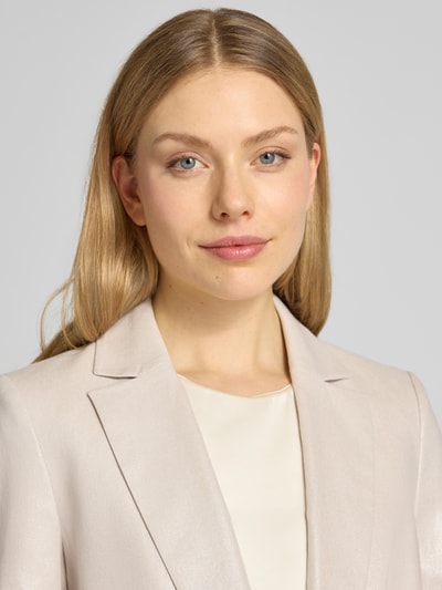 Kobiece model prezentuje Regular Fit Blazer aus Leinen-Mix od Christian Berg Cocktail, jasny beż, gładka tekstura, krój regular fit, bawełniany len, klasyczny kołnierz z klapami, pasplowane kieszenie, zapięcie na guzik, długość tyłu w rozmiarze 36: 68 cm, zbliżenie na górną część ciała.