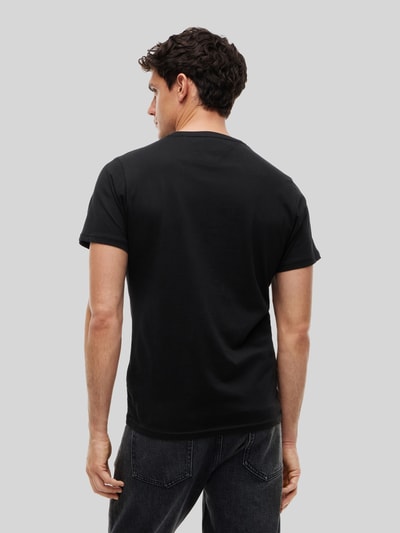 Männermodel trägt schwarzes Slim Fit T-Shirt aus reiner Baumwolle von Tommy Jeans, glatte Textur, Ganzkörperansicht Rückansicht.