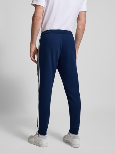 Männermodel trägt Sweatpants mit elastischem Bund von adidas Originals in Dunkelblau, Baumwoll-Mix, Lockerer-Schnitt, Ganzkörperansicht Rückansicht.