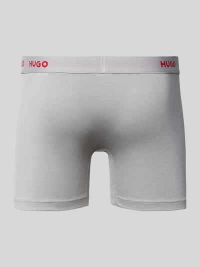 Männermodel trägt Pant & Trunk aus Baumwoll-Mix im 3er-Pack von HUGO, hellgrau mit rotem Logo, Ganzkörperansicht Rückansicht, Herren.