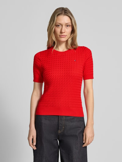 Frauenmodel trägt Slim Fit T-Shirt aus reiner Baumwolle von Tommy Hilfiger, Optik: Unifarben, Zopfmuster, Logo-Detail, Strick, Rundhals, Kurzarm, Gerippt, Ganzkörperansicht von vorne.
