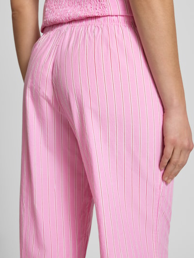 Frauenmodel trägt Wide Fit Pyjama-Hose mit elastischem Bund Modell 'Poplin' von Gina Tricot in Rosa mit weißen Streifen, Nahaufnahme Rückansicht, elastischer Bund, weiche Poplin-Textur, Damen Pyjama-Hose mit Tunnelzug, Bundweite S 36 cm, Innenbeinlänge S 78 cm.