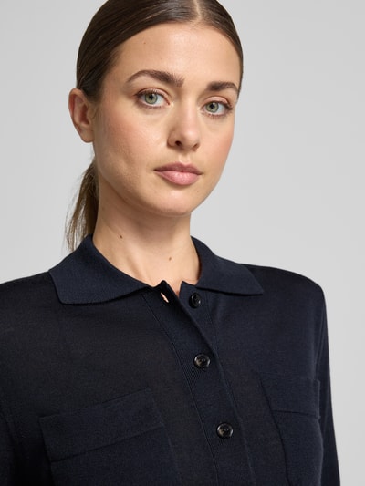 Frauenmodel trägt Strickjacke aus reiner Schurwolle Modell 'DETTO' von MM by Max Mara in Dunkelblau, sichtbare Knopfleiste, fein strukturierte Textur, Nahaufnahme Oberkörper.