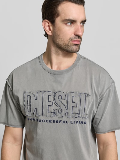 Männermodel trägt Regular Fit T-Shirt mit Logo-Detail von Diesel in Grau, Reine Baumwolle, Rundhalsausschnitt, Kurzärmelig, Nahaufnahme Oberkörper.
