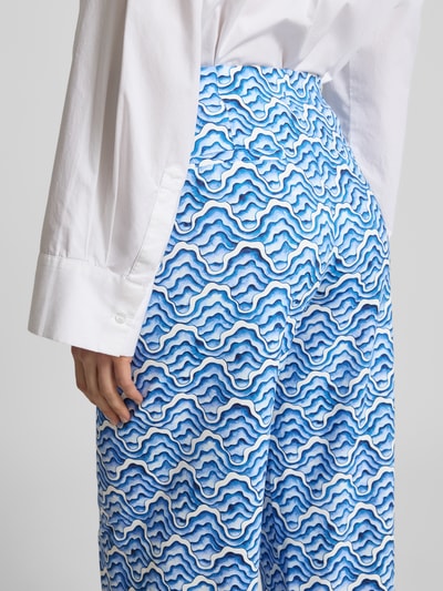 Frauenmodel trägt Wide Fit Stoffhose mit elastischem Bund von HERZENS, blaues Wellenmuster, Gesäßtaschen, Detailaufnahme Rückansicht.