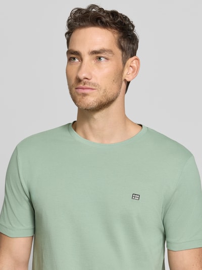 Männermodel trägt T-Shirt aus Baumwolle mit Rundhalsausschnitt von Christian Berg Men, Reine Baumwolle, Regular-Fit, Label-Detail, Nahaufnahme Oberkörper.