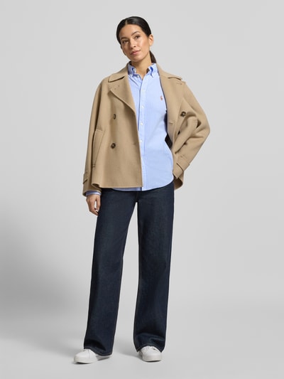 Frauenmodel trägt Regular Fit Hemdbluse aus reiner Baumwolle Modell 'HEIDI' von Polo Ralph Lauren, blauer Stoff mit feinen Streifen, Button-Down-Kragen, aufgesetzte Knopfleiste, kleine Logo-Stickerei auf Brusthöhe, 1-Knopf-Manschetten, Piqué-Struktur, kombiniert mit weiter dunkelblauer Hose und beigefarbener Jacke, Rückenlänge bei Größe S 70 cm, Ärmellänge 64 cm, Ganzkörperansicht von vorne.