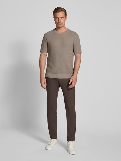 Männermodel trägt Slim Fit Chino aus Baumwoll-Mix von bugatti in Braun mit Münztasche, Gesäßtaschen, Ganzkörperansicht von vorne.