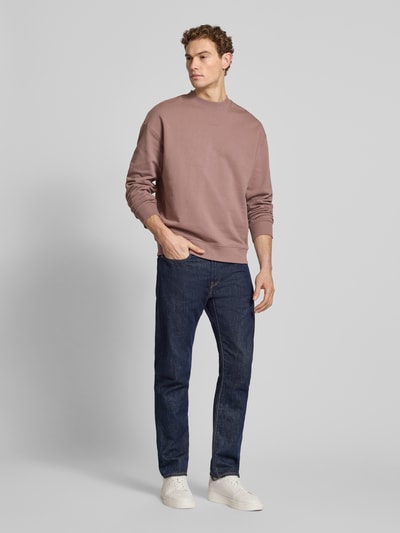 Männermodel trägt Regular Fit Sweatshirt aus reiner Baumwolle Modell 'DAPOCREW' von HUGO, braun, unifarben, Rundhals, Ganzkörperansicht von vorne.