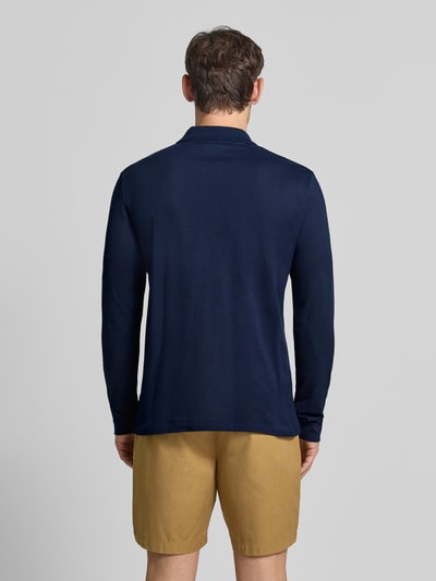 Männermodel trägt Regular Fit Poloshirt aus reiner Baumwolle von Lacoste in Dunkelblau, glatte Struktur, Ganzkörperansicht Rückansicht.