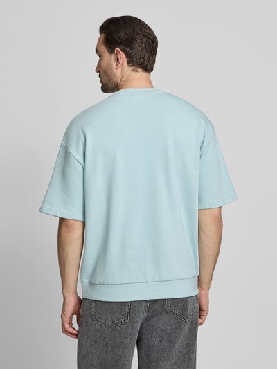 Männermodel trägt Oversized T-Shirt mit Rundhalsausschnitt von Lindbergh, Baumwoll-Mix, Label-Detail, Rückenlänge 70 cm, Ganzkörperansicht Rückansicht.