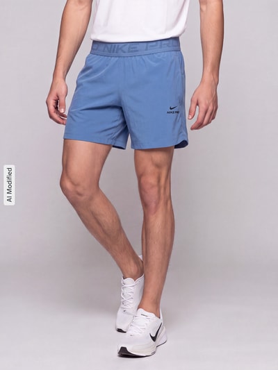 Männermodel trägt Regular Fit Sportshorts mit Dri-FIT-Technologie von Nike, hellblau, glatte Textur, Herren Sportshorts von Nike Training, Ganzkörperansicht von vorne, KI-modifiziertes Bild.