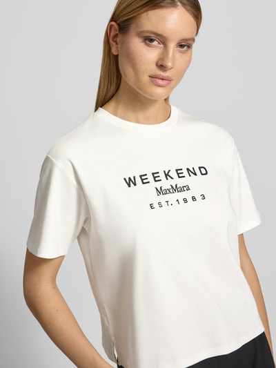 Kobiece model nosi damski t-shirt Regular Fit T-Shirt aus reiner Baumwolle Modell 'SABATO' od Weekend Max Mara, efekt: jednolity kolor, krój regular fit, wyhaftowana aplikacja floral, okrągły dekolt, krótki rękaw, wykończenie materiału: drobne prążkowanie, wykonany z czystej bawełny, zdjęcie: zbliżenie na górną część ciała.