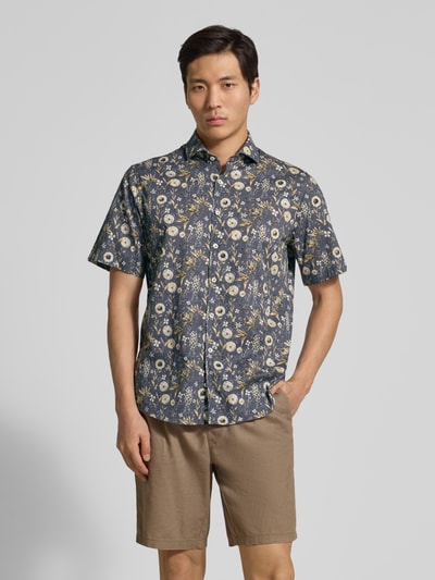 Męski model prezentuje Modern Fit Freizeithemd im Allover-Look Modell 'Hardy' od Brax z krótkim rękawem, wzór kwiatowy, koszulowy kołnierzyk, zapięcie na guziki, długość tyłu w rozmiarze M: 76 cm, szerokość w rozmiarze M: 48 cm, długość rękawa w rozmiarze M: 25 cm, widok całej sylwetki z przodu.