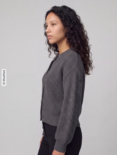 Frauenmodel trägt Loose Fit Strickjacke mit einreihiger Knopfleiste Modell 'LEA' von VERO MODA in Grau mit Strickstruktur, Ganzkörperansicht von vorne, KI-modifiziertes Bild.