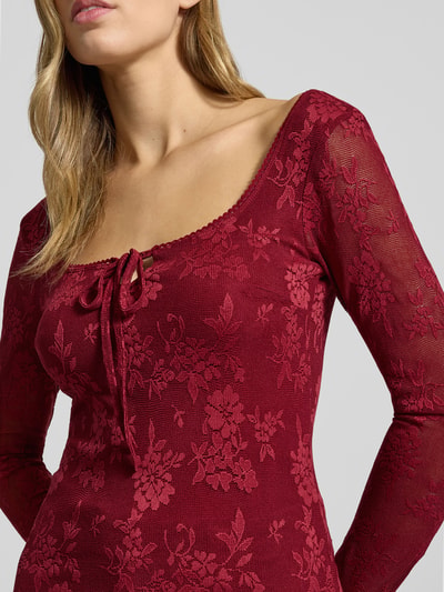 Kobiece model nosi semitransparentne Longsleeve z wiązaniem od Gina Tricot, mieszanka materiałów z dodatkiem streczu, krój slim fit, prostokątny dekolt, półprzezroczysty materiał, długość tyłu 29 cm, rozmiar S, detaliczny widok na górną część ciała.