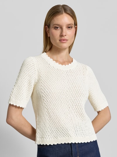 Modelka kobieca nosi Strickshirt mit 1/2-Arm Modell 'Carla' od mbyM, mieszanka bawełny, prosty krój, gruby ścieg, okrągły dekolt, rękaw o dł. 1/2, długość tyłu w rozmiarze S: 54 cm, długość rękawów w rozmiarze S: 32 cm, kremowy kolor, faktura dzianiny, detaliczny wzór, widok na górną część ciała z przodu.