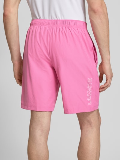 Männermodel trägt Regular Fit Sport-Shorts mit weichem Innenstoff von Lacoste Sport in Rosa, feines Strukturmuster, Ganzkörperansicht Rückansicht.