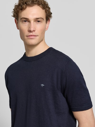 Męski model nosi Regular Fit T-Shirt mit Leinen-Anteil in Strick-Optik von Fynch-Hatton, ciemny niebieski, wyhaftowane logo, mieszanka bawełny i lnu, imitacja dzianiny, elastyczne wykończenia, długość tyłu w rozmiarze M 70 cm, krój regular fit, zbliżenie na górną część ciała