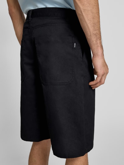Männermodel trägt Bermudas mit Eingrifftaschen von REVIEW, schwarzer Baumwoll-Mix, Regular-Fit, Gesäßtaschen, Ganzkörperansicht Rückansicht.