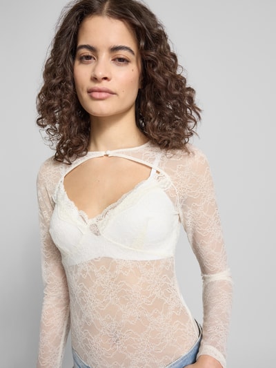 Frauenmodel trägt Longsleeve mit Cut Out von Gina Tricot aus semitransparenter Spitze in Weiß, körpernahe Passform, Nahaufnahme Oberkörper.