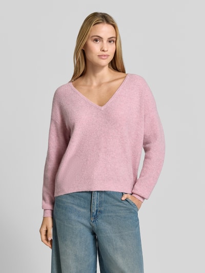 Kobiece modelka ma na sobie sweter z dzianiny z mieszanką lnu Model 'DAMSVILLE' od American Vintage, efekt prążkowania, dekolt w serek, luźny krój, elastyczne wykończenia, Mieszanka materiałów, długość tyłu w rozmiarze XS/S: 61 cm, długość rękawa w rozmiarze XS/S: 54 cm, jasnoróżowy kolor, faktura miękka, całkowity widok z przodu.