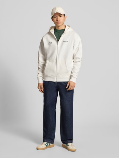 Männermodel trägt Oversized Sweatjacke mit Label-Print Modell 'Rochefort' von Pegador, Baumwoll-Mix, Eingrifftaschen, Kapuze, Reißverschluss, Farbe Creme, Ganzkörperansicht von vorne