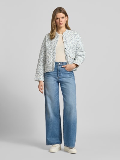 Kobiece modelka nosi Regular Fit Hemdjacke mit Allover-Muster Modell 'HALLIE' od Only, efekt: wzór na całej powierzchni, krój regular fit, stójka, kwiatowy wzór, długi rękaw, kieszenie z patką, jasnoniebieskie i białe odcienie, tekstura miękka, zdjęcie: całopostaciowy widok z przodu.