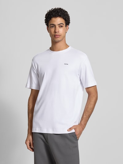 Męski model nosi Regular Fit T-Shirt mit Logo-Print Modell 'True' von G-Star Raw w kolorze białym, okrągły dekolt, krój regular fit, długość tyłu w rozmiarze M: 66 cm, Ganzkörperansicht von vorne.