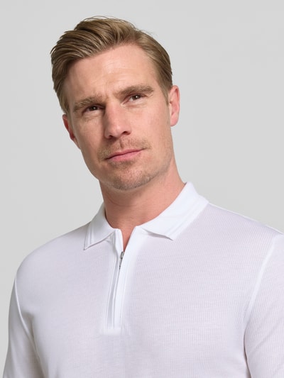 Męski model nosi Regular Fit Poloshirt aus Baumwoll-Lyocell-Mix Modell 'H-PARAS 70' od BOSS, biały, efekt: jednolity kolor, kołnierzyk polo, zamek błyskawiczny, mieszanka bawełny i lyocellu, pika, naszywka z logo, krój regular fit, zapięcie: krótki zamek błyskawiczny, zakończenie rękawów: prążkowane, wykończenie: z bocznymi rozcięciami, materiał: wykończenie materiału pika, ujęcie: zbliżenie na górną część ciała.