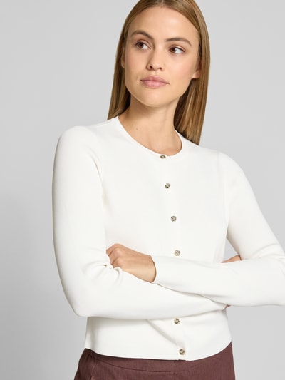 Kobieta prezentuje Slim Fit Cardigan aus Viskose-Mix Modell 'Velda' od Ted Baker, imitacja dzianiny, z długim rękawem, okrągły dekolt, listwa guzikowa, długość tyłu w rozmiarze 36: 47 cm, długość rękawów: 63 cm, kolor biały, prosta faktura, widok na górną część sylwetki z przodu.