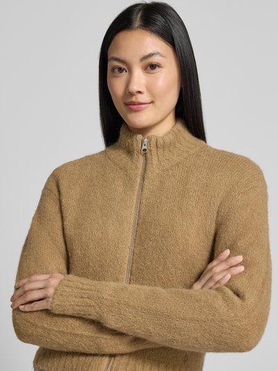 Kobiece model nosi Regular Fit kurtka z mieszanki wełny z alpaki, model 'Jeanne' od Samsøe Samsøe, imitacja dzianiny, beżowa, zamek błyskawiczny dwustronny, stójka, długość tyłu w rozmiarze S: 46 cm, długość rękawów w rozmiarze S: 57 cm, zbliżenie na górną część ciała.