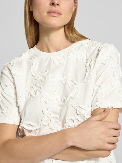 Frauenmodel trägt Blusenshirt mit floraler Zier-Applikation von JAKE*S STUDIO WOMAN aus reiner Baumwolle, Nahaufnahme Oberkörper.