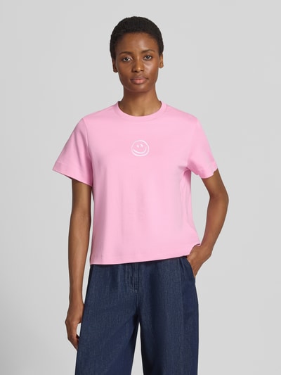 Vrouwenmodel draagt Boxy Fit t-shirt uit pure katoen model 'SARA' van VERO MODA, lichtroze met witte print, dames t-shirt, frontale totaalopname.