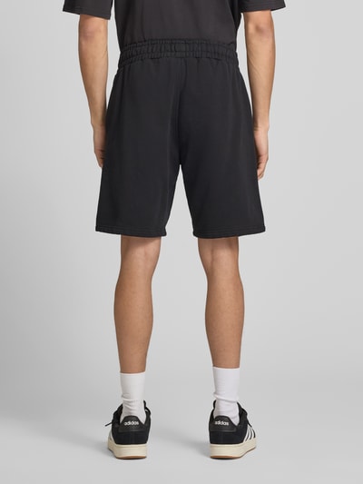 Männermodel trägt Shorts mit elastischem Bund und Logo-Stitching von Pegador aus Baumwoll-Mix, Loose-Fit, französische Eingrifftaschen, Ganzkörperansicht Rückansicht.